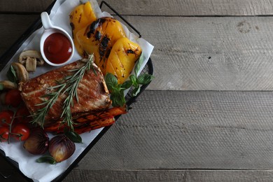 Photo of Delicious grilled meat and vegetables served with sauce on wooden table, top view. Space for text