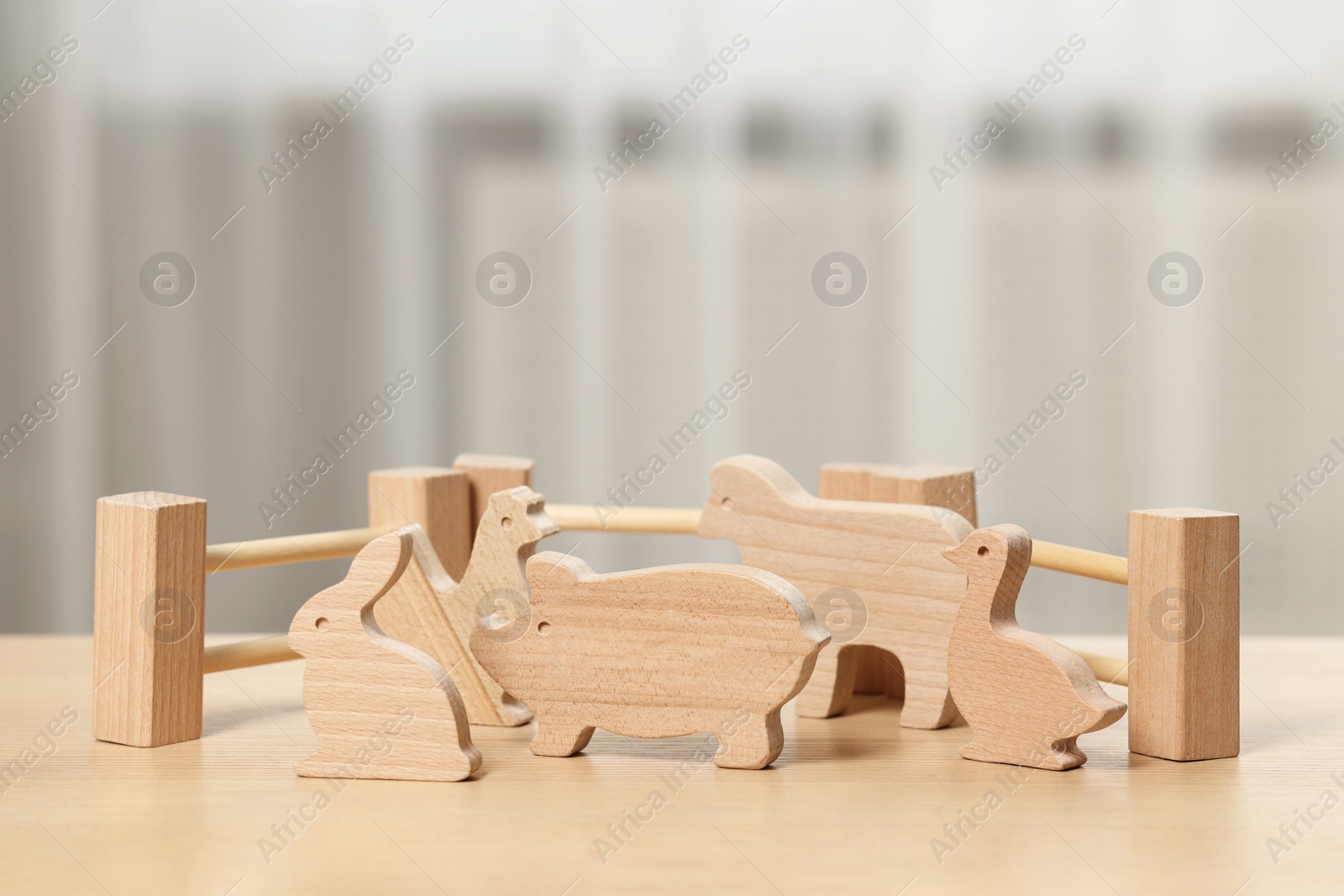 Photo of Wooden animals and fence on table indoors. Children's toys