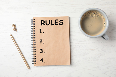 Image of Notebook with list of rules and cup of coffee on wooden background, flat lay