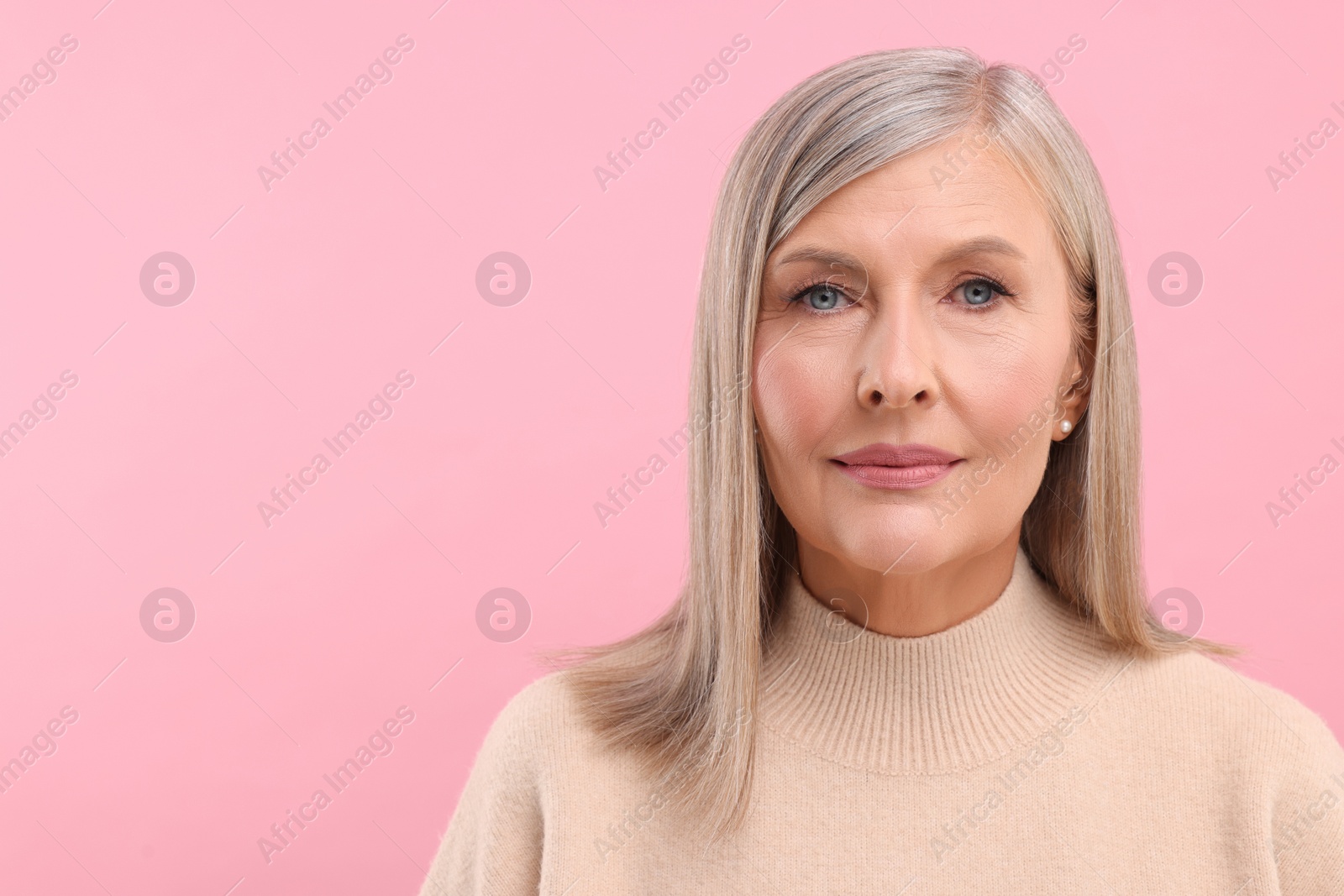 Photo of Portrait of beautiful middle aged woman on pink background, space for text