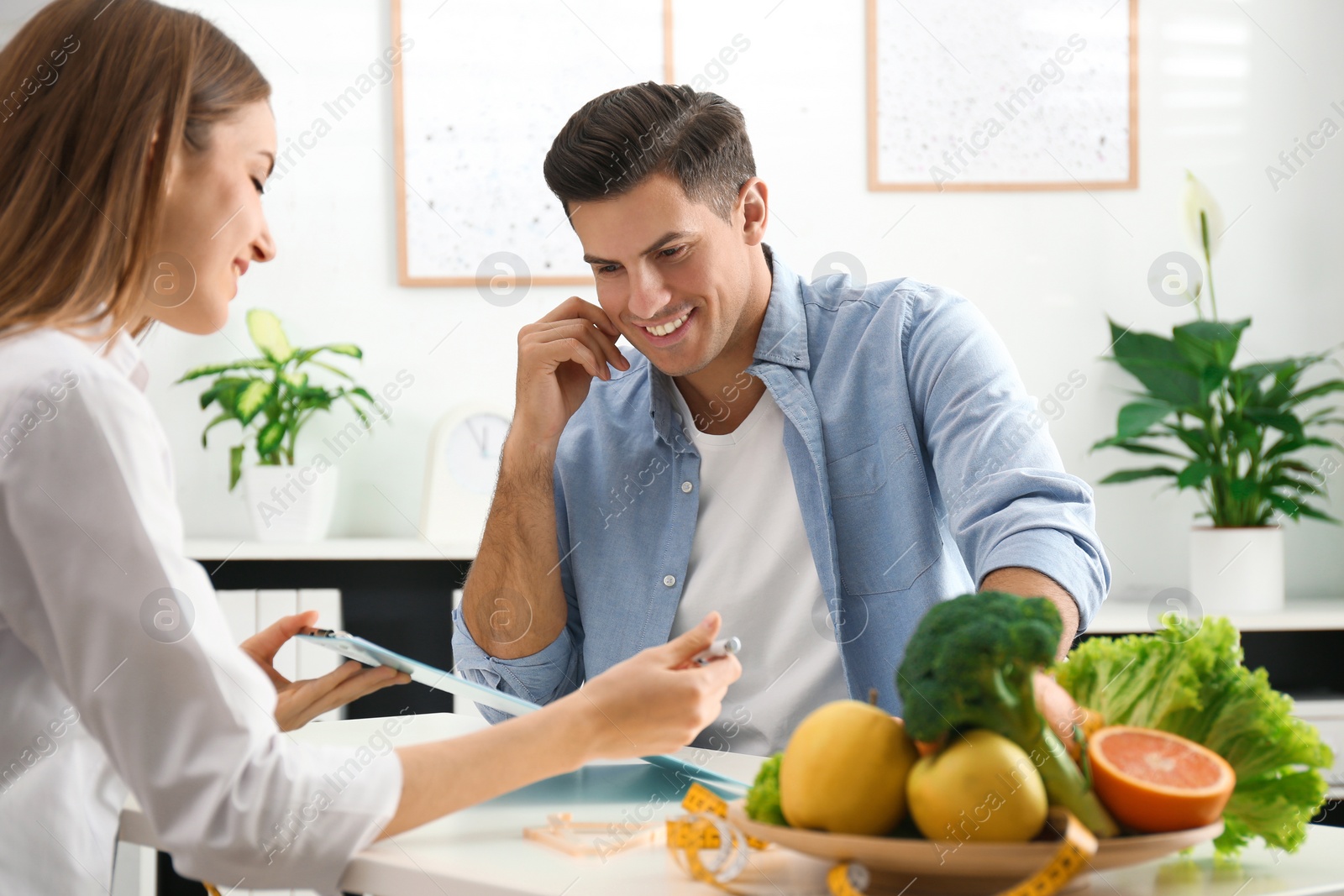 Photo of Young nutritionist consulting patient at table in clinic