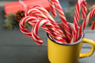 Photo of Many sweet candy canes in cup on grey table, closeup. Traditional Christmas treat