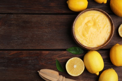 Delicious lemon curd and fresh fruits on wooden table, flat lay. Space for text