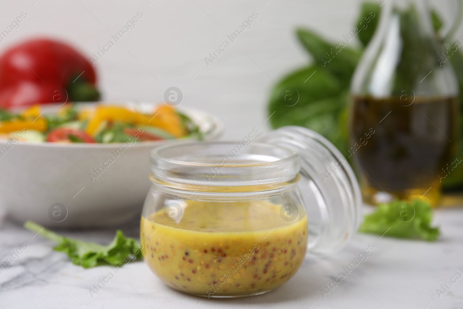 Photo of Tasty vinegar based sauce (Vinaigrette) in jar on white marble table, closeup