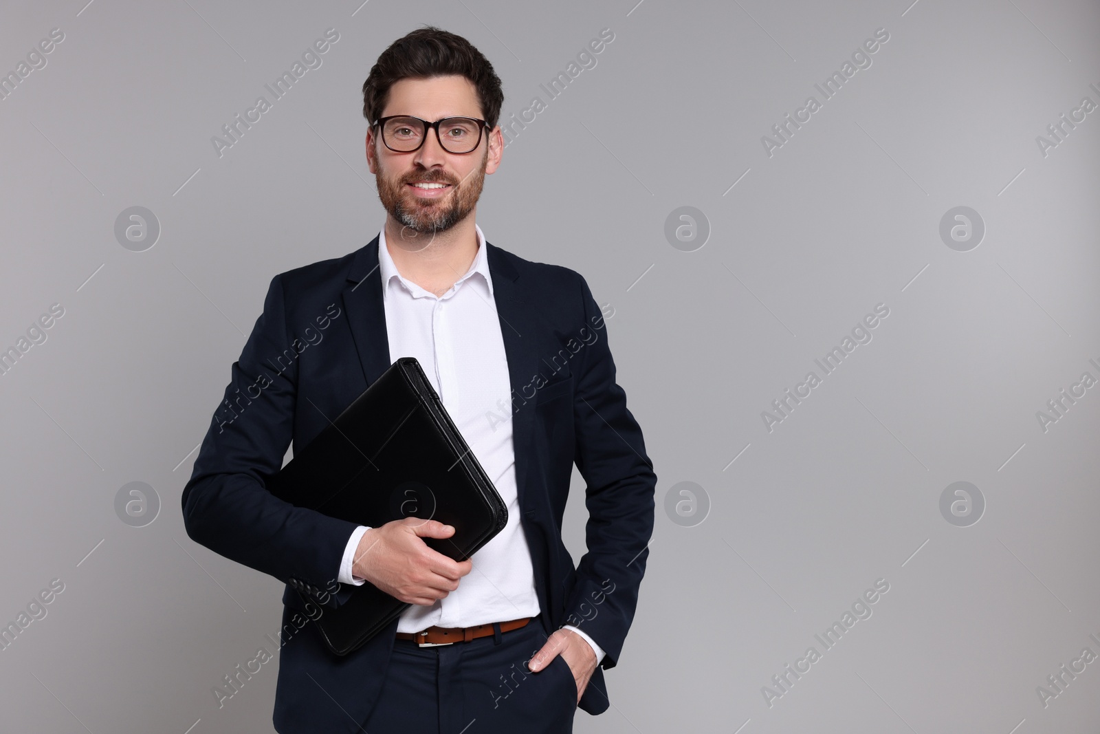 Photo of Happy real estate agent with leather portfolio on grey background. Space for text