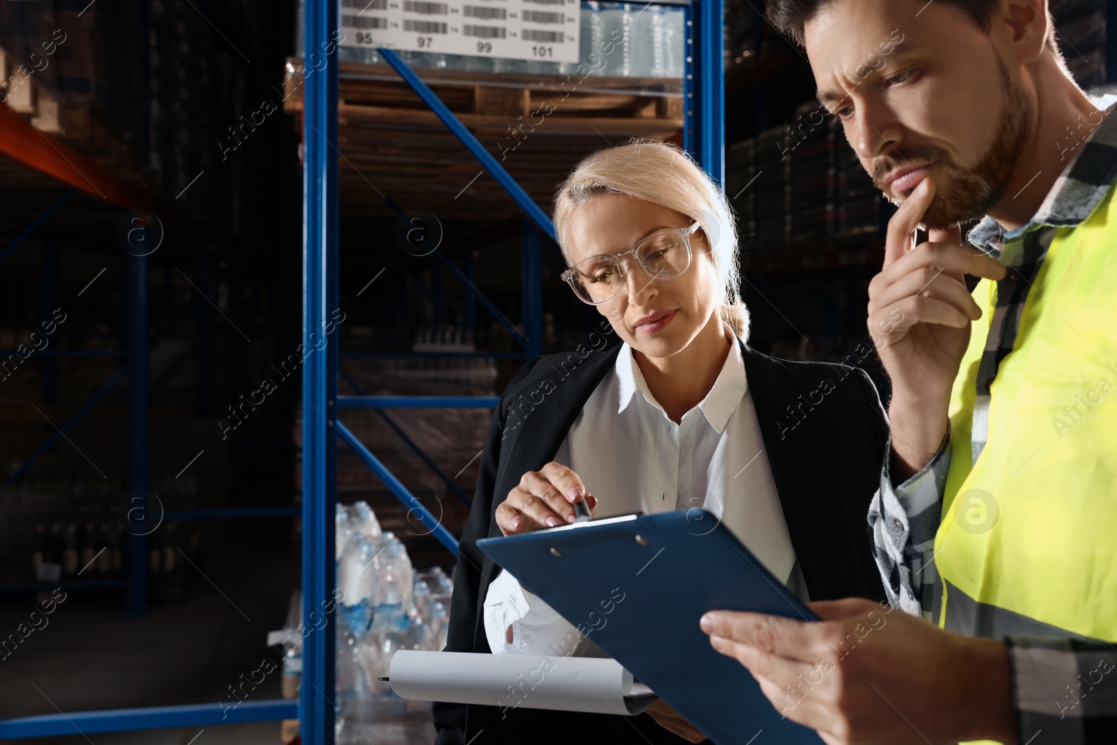 Photo of Manager and worker in warehouse with lots of products