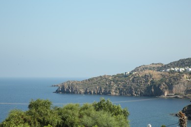 Beautiful view of calm sea, green trees and coastal city on summer day