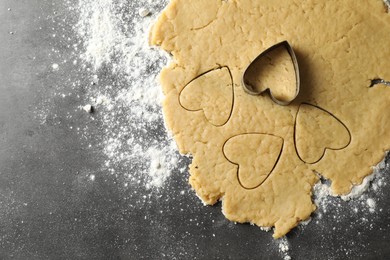 Making shortcrust pastry. Raw dough and cookie cutter on grey table, top view. Space for text