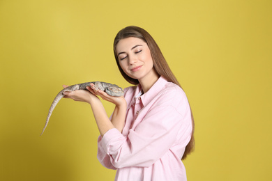 Woman holding bearded lizard on yellow background. Exotic pet