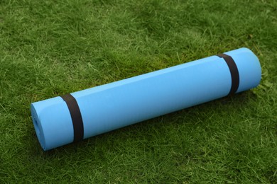 Photo of Bright karemat or fitness mat on fresh green grass outdoors