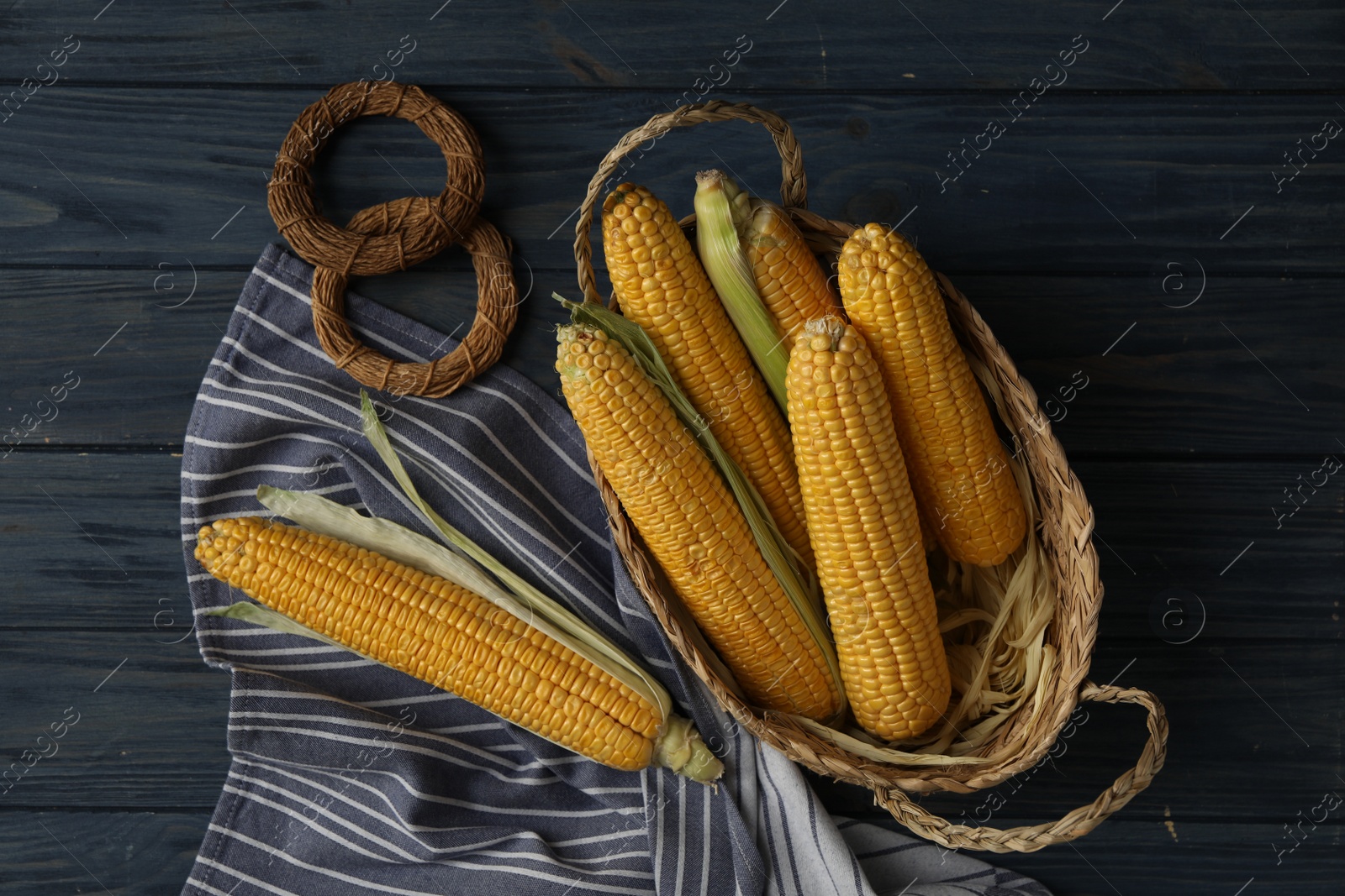 Photo of Corn cobs on dark wooden table, flat lay