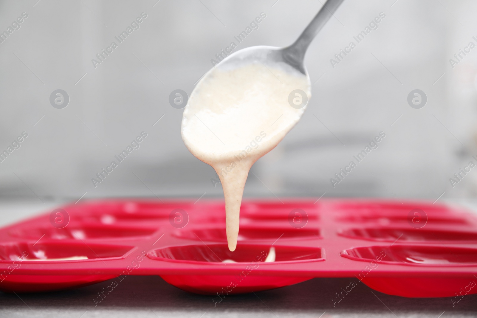 Photo of Woman pouring batter into baking mold at table, closeup. Madeleine cookies