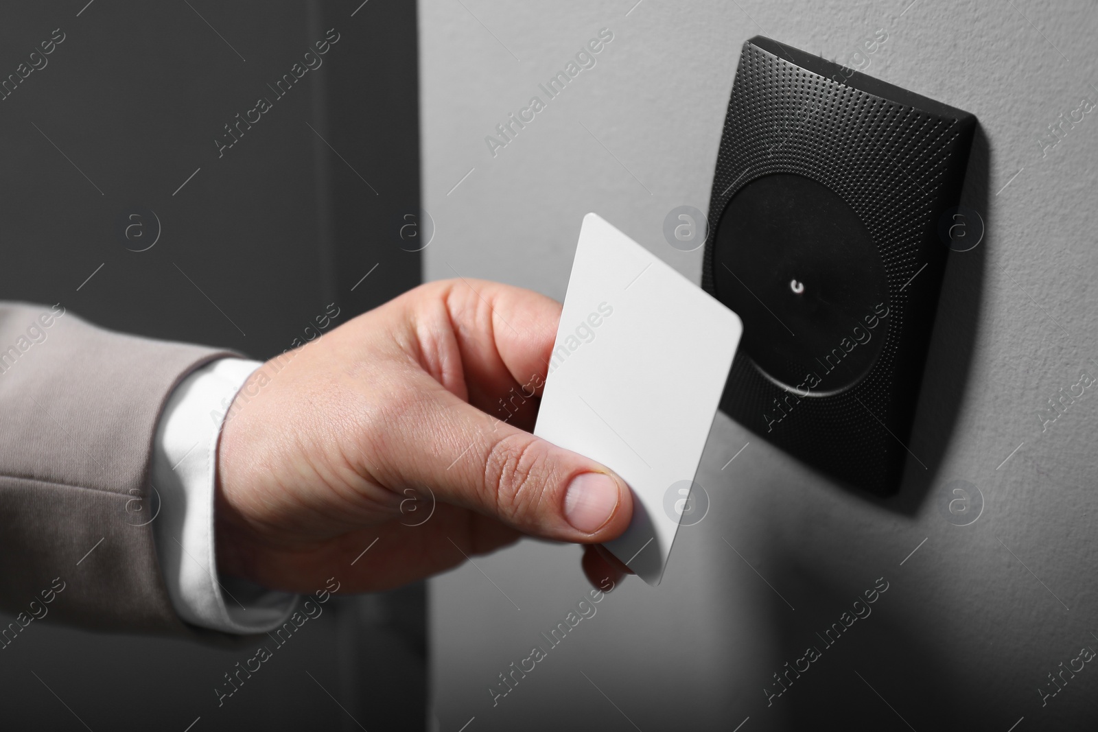 Photo of Man opening magnetic door lock with key card, closeup. Home security