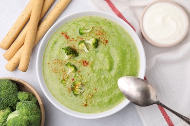 Photo of Delicious broccoli cream soup served on light table, flat lay