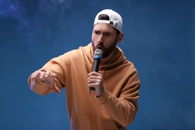 Singer with microphone rapping on blue background