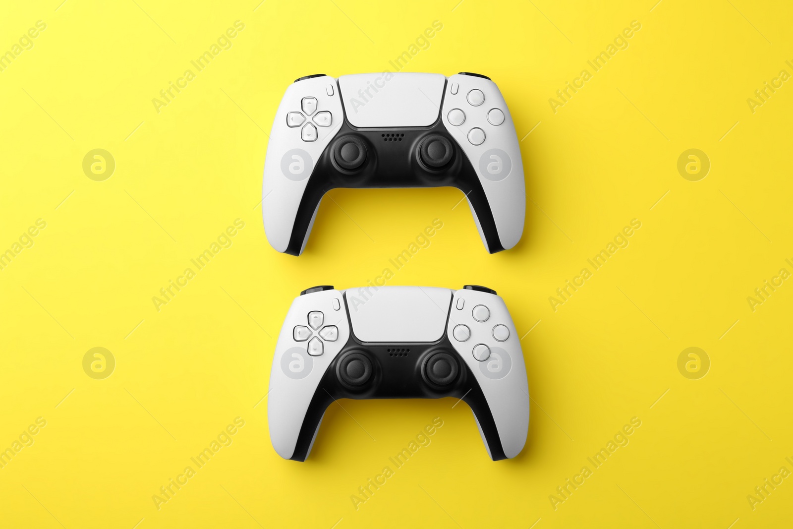 Photo of Wireless game controllers on yellow background, flat lay