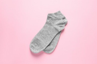 Pair of grey socks on pink background, flat lay