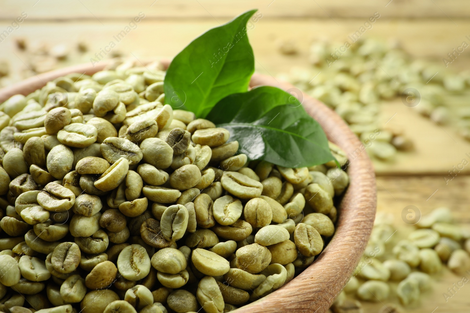 Photo of Green coffee beans and leaves on table, closeup