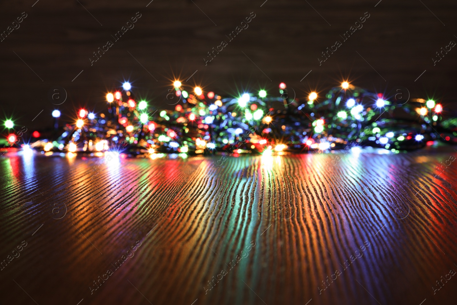 Photo of Beautiful colorful Christmas lights on wooden table. Space for text