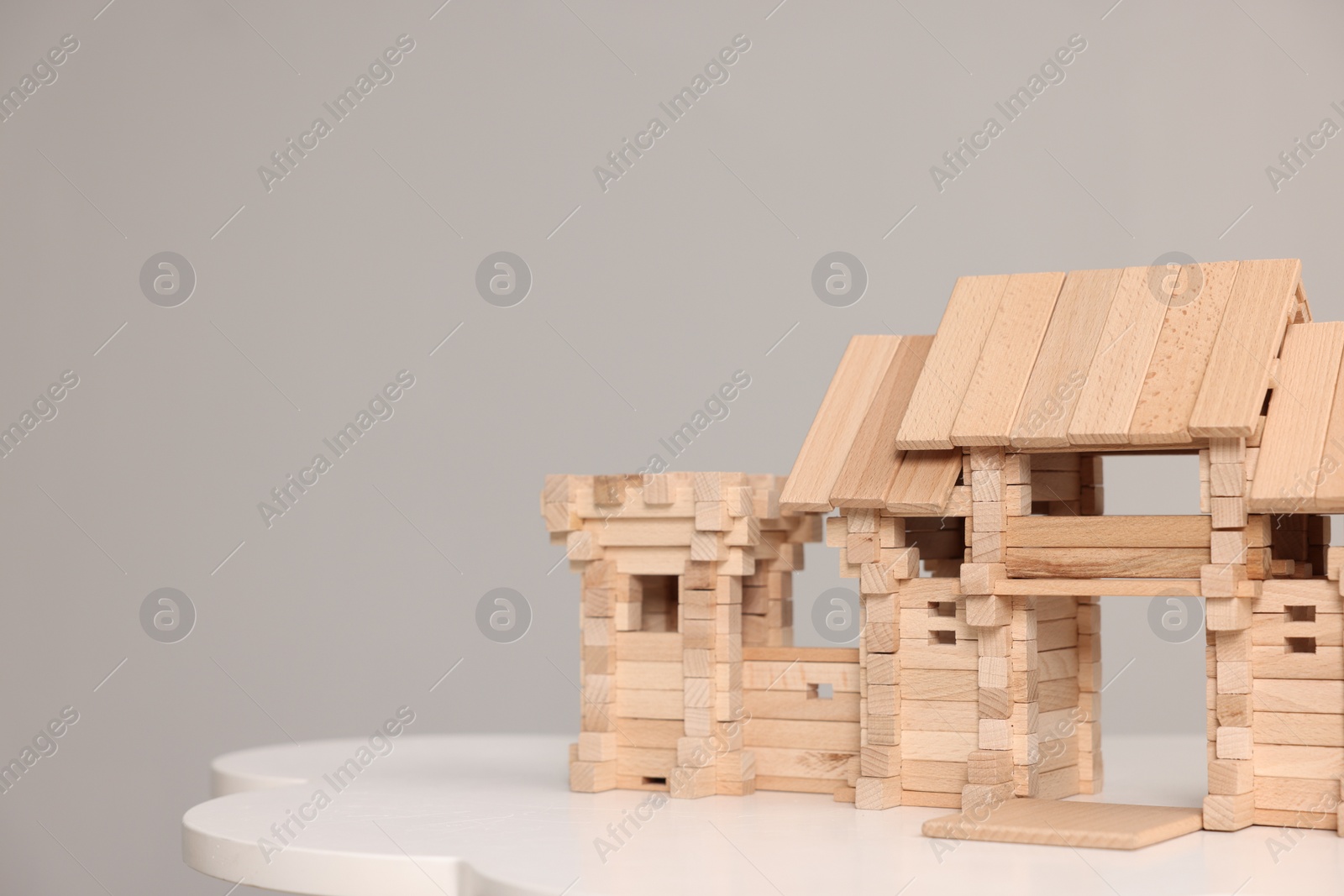 Photo of Wooden entry gate and box on white table against light grey background, space for text. Children's toy