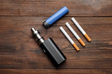Photo of Cigarettes, lighter and vaping device on wooden background, flat lay. Smoking alternative
