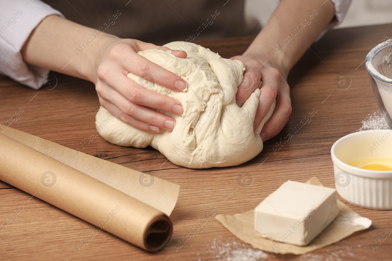 Photo of Woman kneading yeast dough for cake at wooden table, closeup