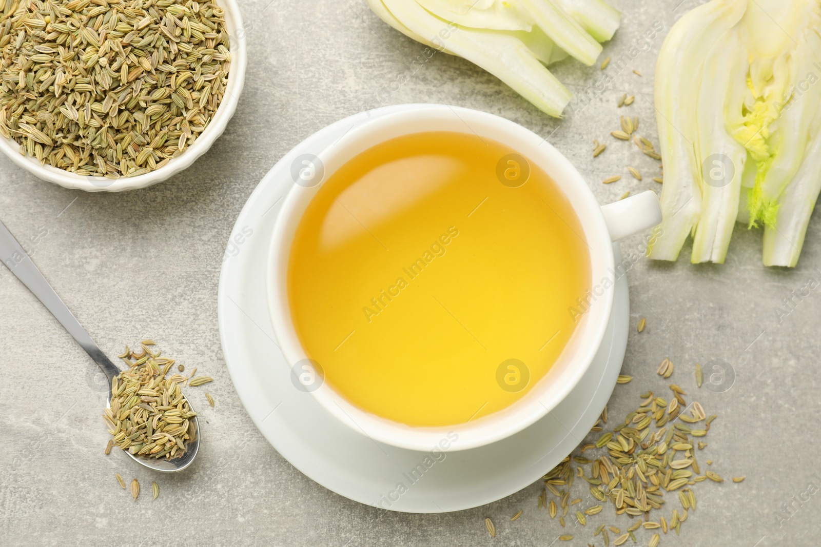 Photo of Aromatic fennel tea, seeds and fresh vegetable on grey table, flat lay