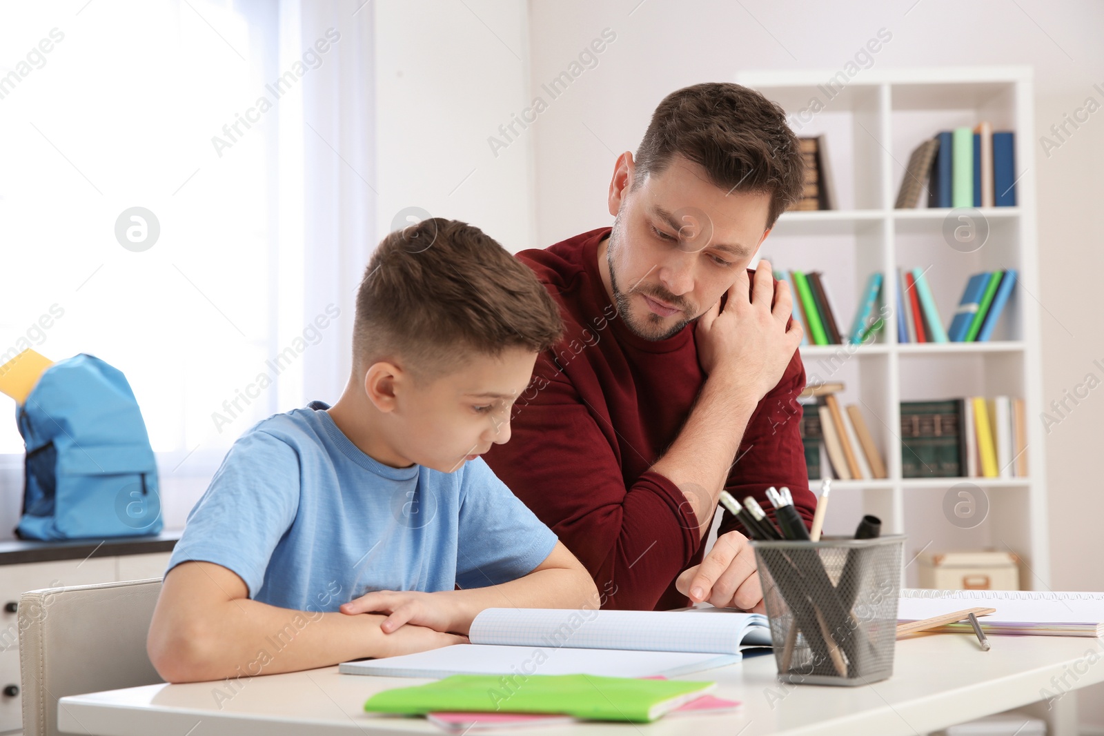 Photo of Dad helping his son with homework in room