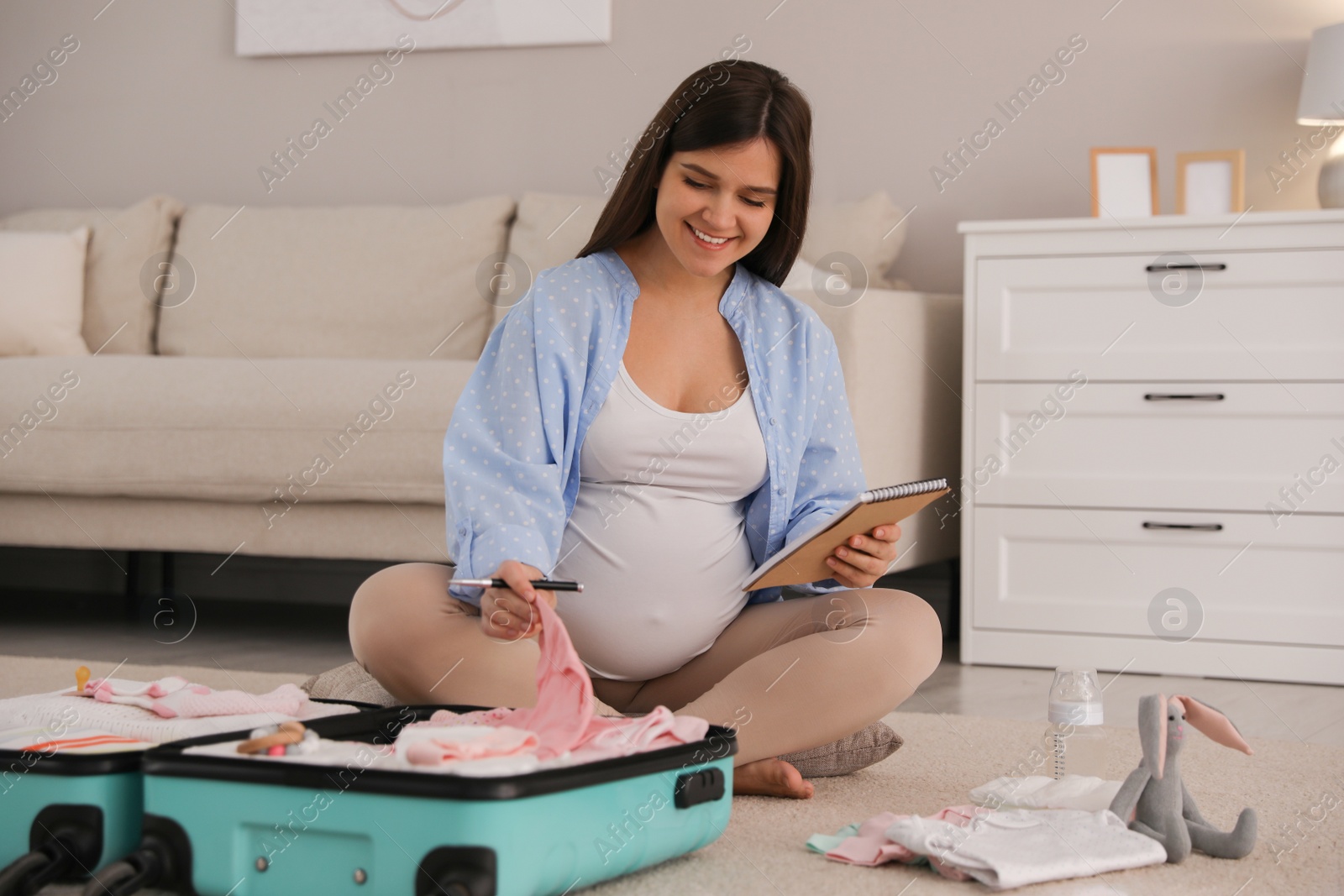 Photo of Pregnant woman packing suitcase for maternity hospital at home