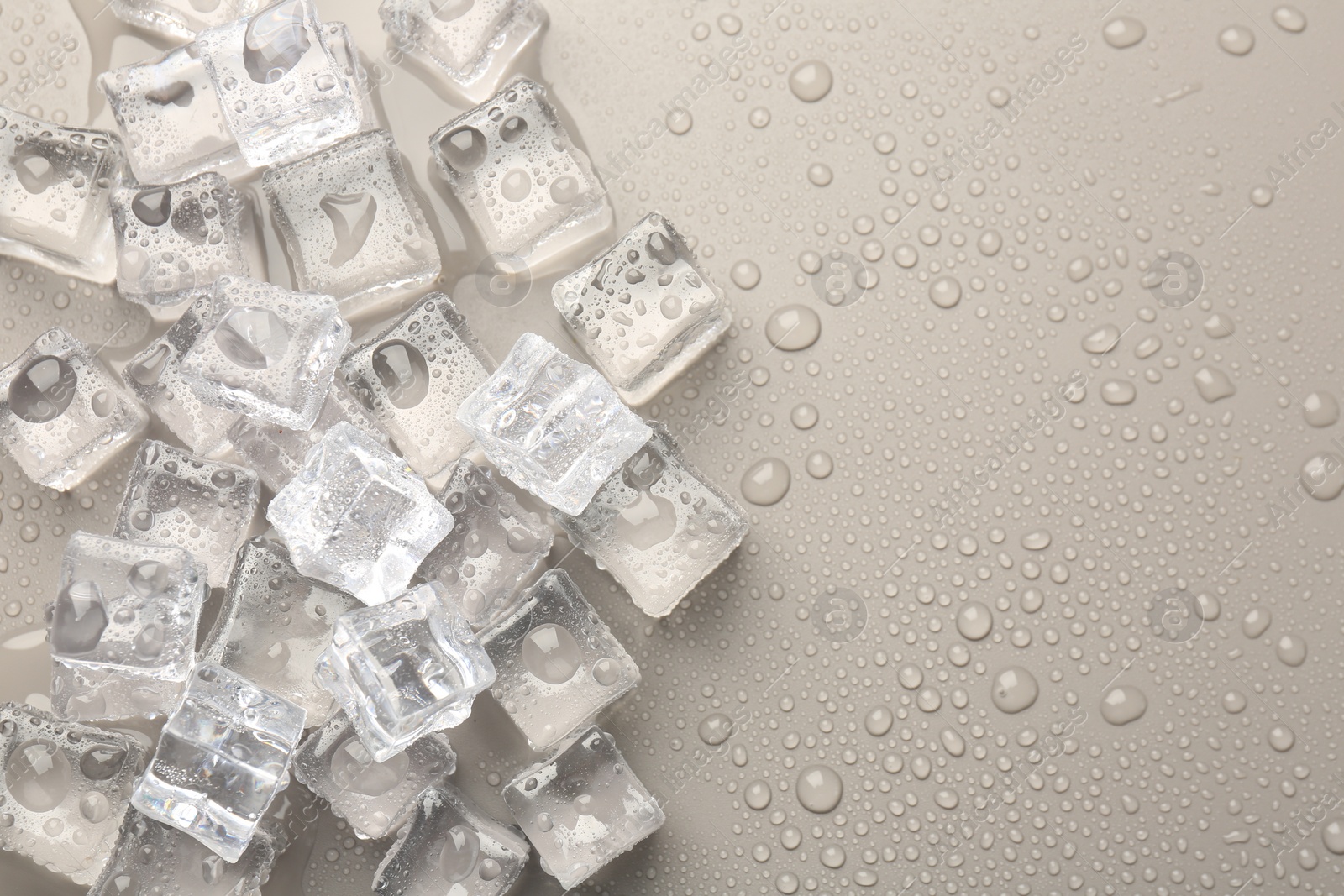 Photo of Melting ice cubes and water drops on light grey background, flat lay. Space for text