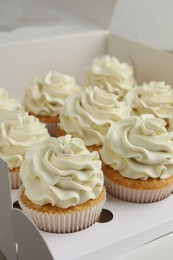 Tasty cupcakes with vanilla cream in box, closeup