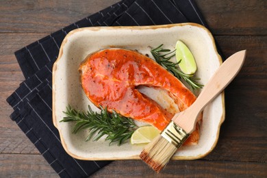 Photo of Fresh marinade, fish, rosemary, lime and brush on wooden table, top view