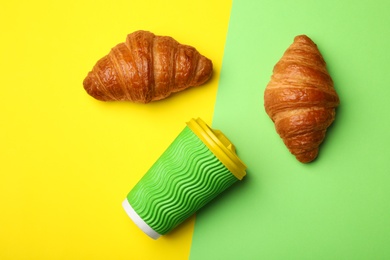 Photo of Paper coffee cup and croissants on color background, flat lay