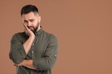 Portrait of sad man on brown background, space for text