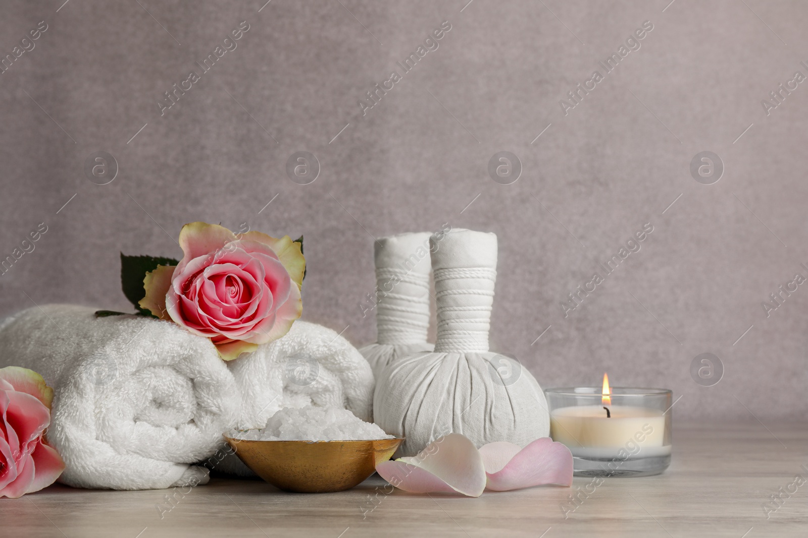 Photo of Composition with spa products, roses and candle on grey wooden table. Space for text