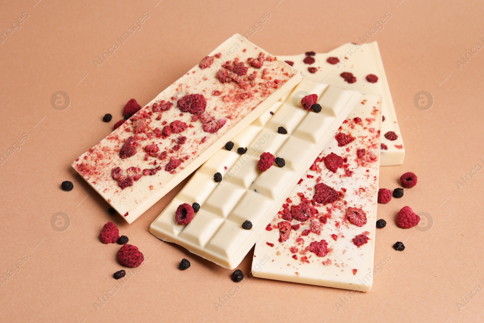 Photo of White chocolate bars with freeze dried fruits on beige background