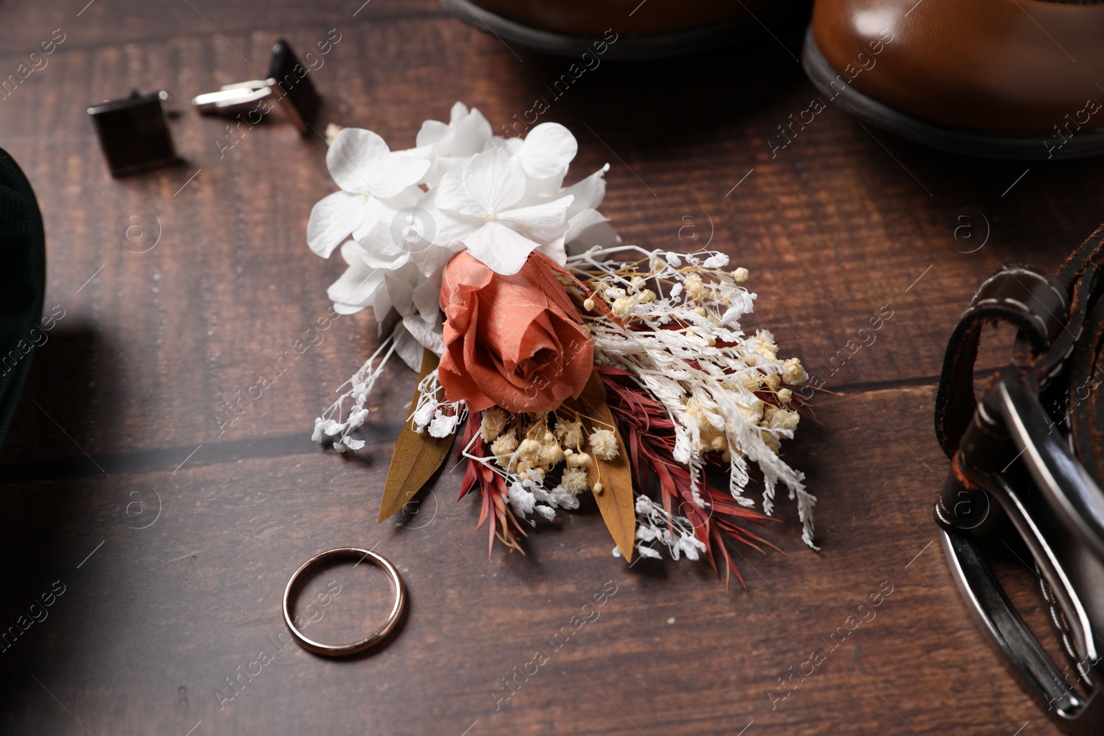 Photo of Wedding stuff. Composition with stylish boutonniere on wooden background, closeup