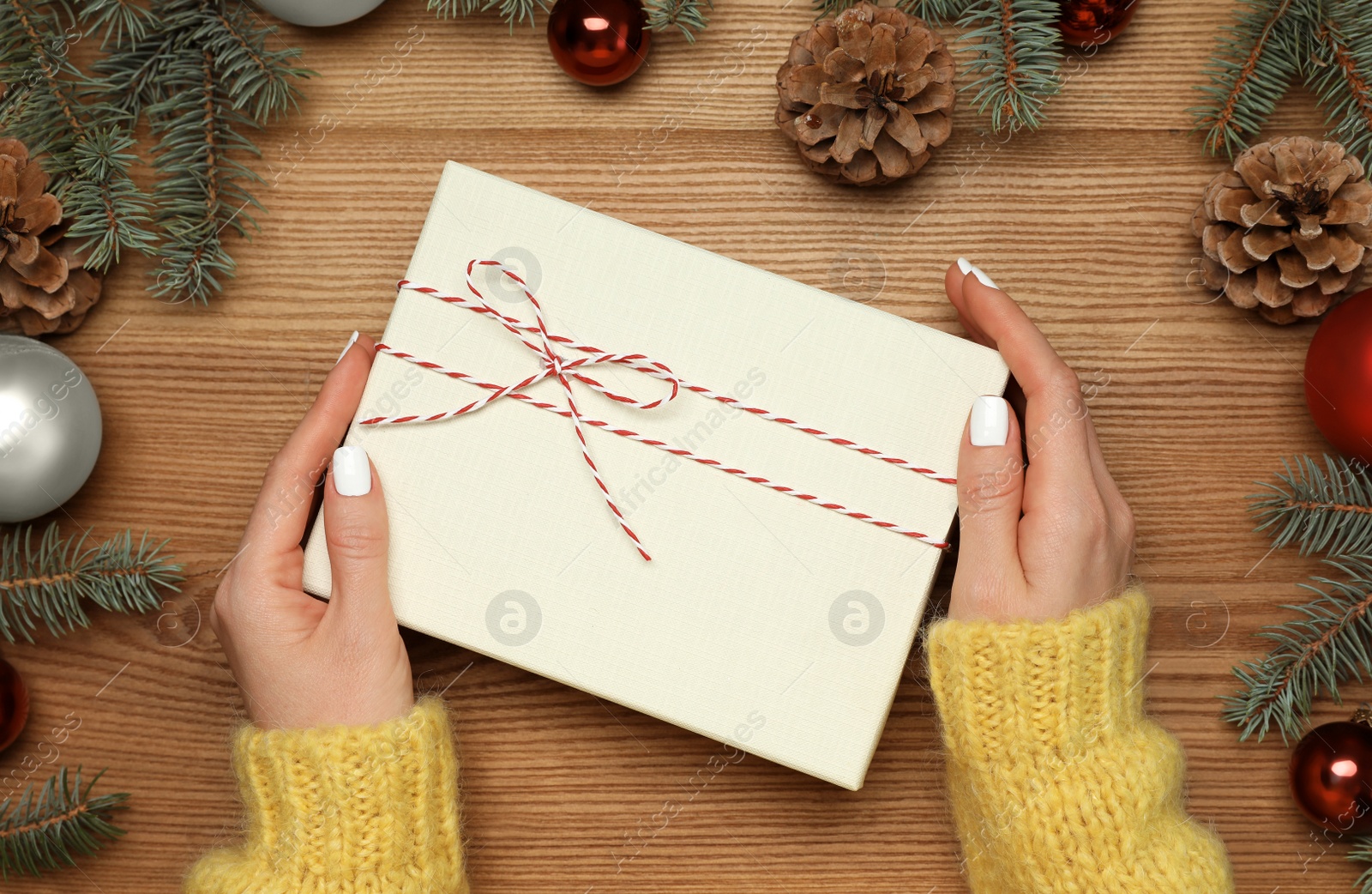 Photo of Woman with Christmas gift at wooden table, top view