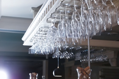 Photo of Set of empty clean glasses on bar racks