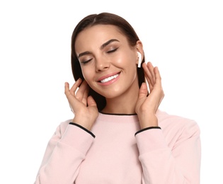 Happy young woman listening to music through wireless earphones on white background