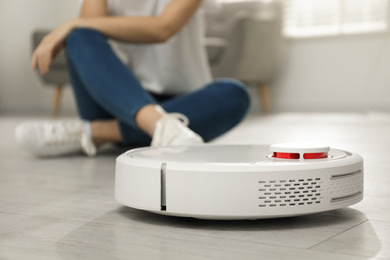 Photo of Woman using robotic vacuum cleaner at home
