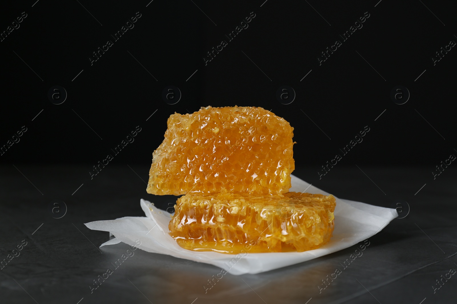 Photo of Natural honeycombs on dark table against black background