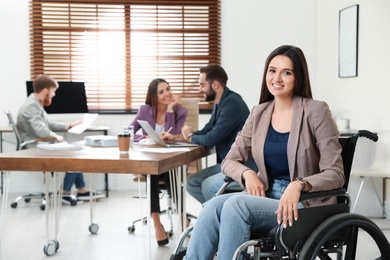 Young woman in wheelchair with colleagues at office