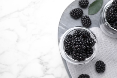 Photo of Fresh ripe blackberries on white marble table, flat lay. Space for text