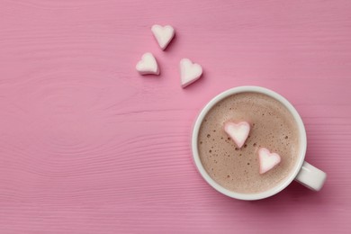 Photo of Cup of aromatic coffee with heart shaped marshmallows on pink wooden table, flat lay. Space for text