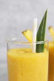 Photo of Tasty pineapple smoothie on light gray background, closeup