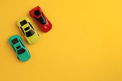 Photo of Different bright cars on yellow background, flat lay with space for text. Children`s toys