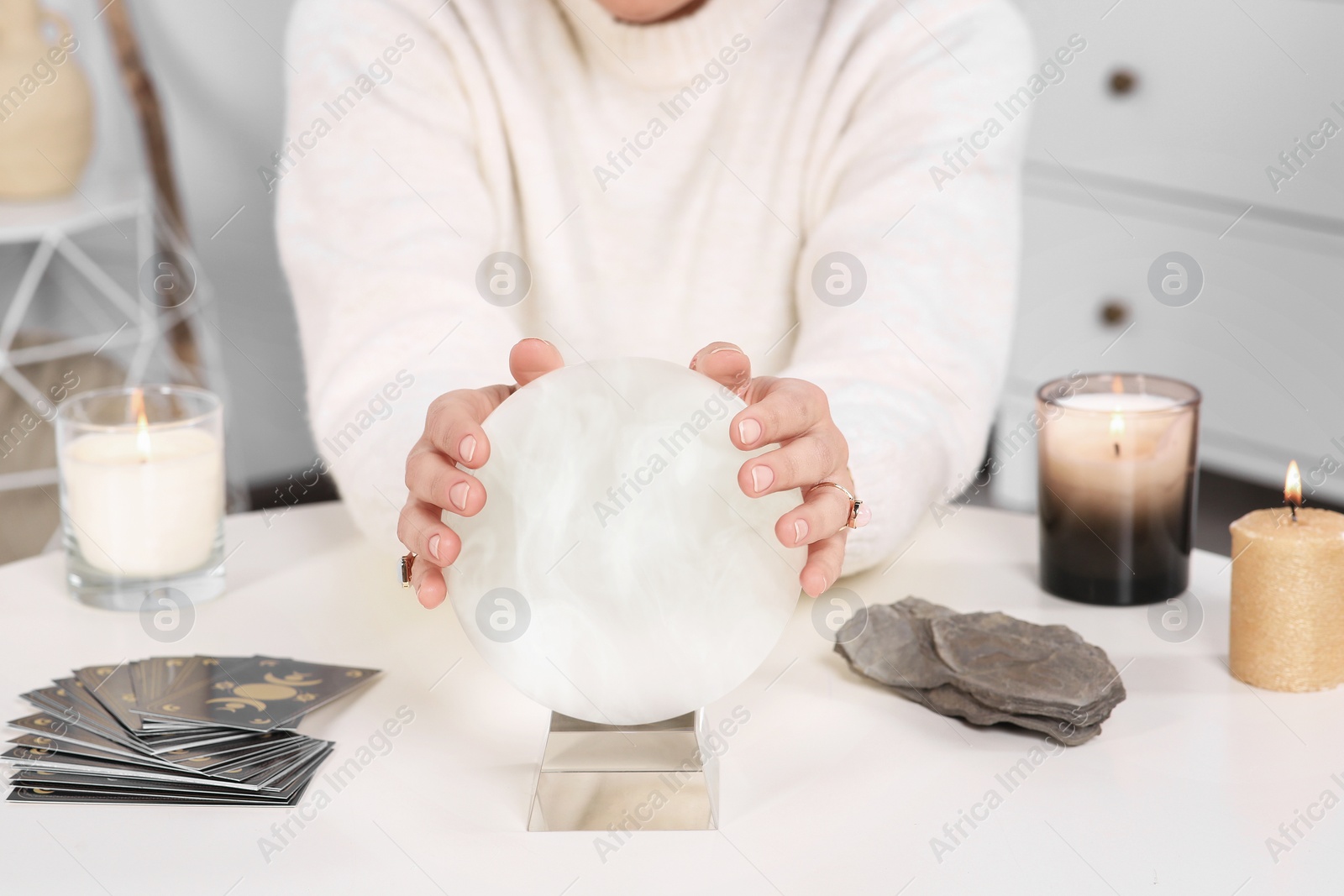 Photo of Soothsayer using crystal ball to predict future at table indoors, closeup