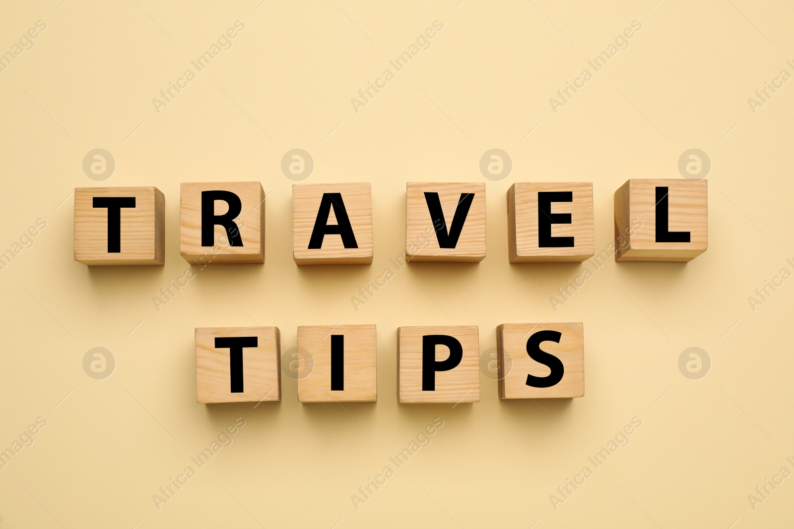 Photo of Phrase Travel Tips made with wooden cubes on yellow background, flat lay