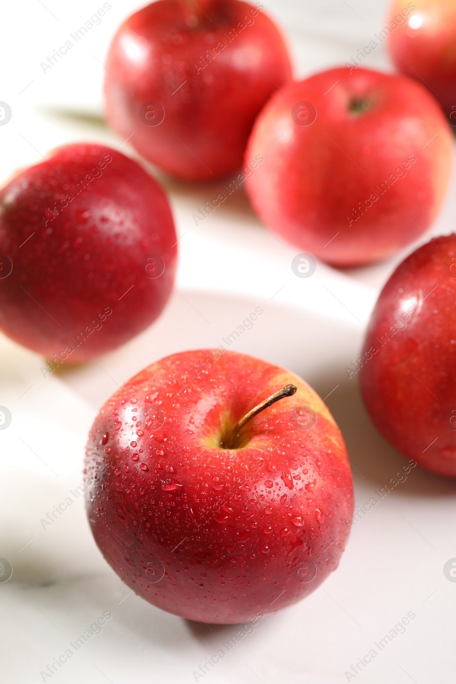 Photo of Fresh red apples with water drops on white table, closeup